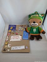 Photo of the soft Sumi mascot plush toy alongside assorted Expo and Olympic pins displayed on a board.