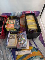 Photo showing stacks of Pokémon cards in boxes and tins on a colorful 2017 Pokémon playmat