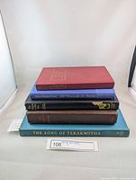 Stack of five vintage hardcover books with visible titles including The Song of Tekakwitha on bottom and Treasure Island on top of the stack.