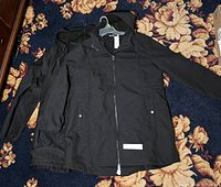 Two black women's jackets laid flat on floral carpet, showing front side with hoods and zippered fronts.