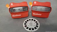 Top view showing two red View-Master viewers with orange levers and one circular View-Master reel.
