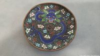 Full view of the round cloisonné plate showing the blue dragon and floral patterns on engraved enamel surface.