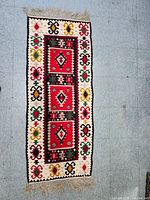 Full view of rectangular kilim rug laid on floor showing geometric diamond designs and colorful border patterns