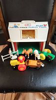Overall view of white barn and all farm animals and accessories grouped in front on a chair