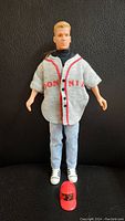 Full view of 12-inch Donnie doll wearing jersey, jeans, and shoes, standing against black backdrop