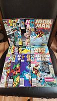 Photo shows all 12 Marvel Iron Man comic books arranged in two rows, different colorful covers visible including Iron Man in action and other characters.