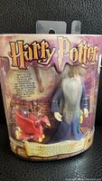 Front view of sealed Harry Potter Albus Dumbledore figure with Fawkes in original packaging showing logo and character clearly.