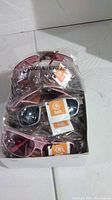 Box containing multiple pairs of new sunglasses in various styles and colors, sealed in plastic packaging.