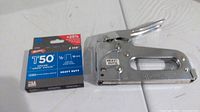 Photo showing the Arrow T-50p heavy duty stapler next to a box of T50 staples on a white surface.
