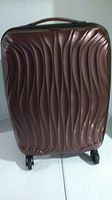 Front view of Lucas hard sided carry-on suitcase in burgundy with textured wavy exterior and base wheels