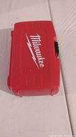 Closed red plastic Milwaukee drill bit case with white logo on top.