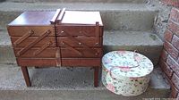 Closed wood multi-tiered sewing box and closed floral round hat box on steps