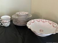Photo showing stack of floral plates, cups, and large scalloped bowl with bridal rose pattern and gold trim.