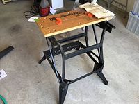 Workmate 200 table showing wooden top, black metal frame legs, and orange clamps with instruction manual on top.