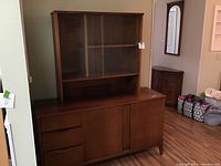 Front view of vintage wooden china cabinet showing drawers on the left, two cabinet doors on the right, and the glass display cabinet on top.