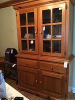 Full front view of pine china cabinet showing the two glass paneled upper doors with shelves inside and lower drawers and cupboards.