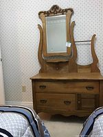 Full view of antique light-colored wood dresser with attached large mirror, decorative carved top, shelf underneath mirror, and small side rack. Shows overall condition and design.