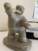 Soapstone figure of Inuit hunter holding a spear, signed DIMU, posed with right arm up and left forward.