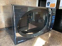 Black Danby Designer microwave oven shown on a kitchen counter, front angled view revealing front door and control panel.