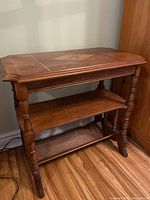 Full view of the wooden side table showing parquet decorated top, turned legs, and two lower shelves