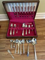Full set of flatware in wooden box with red velvet lining, knives in lid, forks and spoons in base, extra pieces outside box