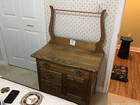 Front view of antique light wood wash stand with backboard and towel rack, two drawers and cupboard below.