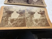 Photo of stereoview card showing Stand Rock, Dells of the St. Croix, Wisconsin, with dual sepia images of a natural rock formation with a person jumping between rocks.