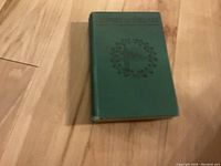 Book closed on wooden floor showing green cloth cover with embossed design and title 'History of Ireland'
