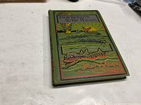 Front cover of the green hardcover book titled 'From The Earth To The Moon' by Jules Verne, featuring illustrated sea scene and hot air balloon.