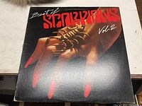 Front cover of vinyl record album Best Of Scorpions Vol. 2 showing art of a hand holding a golden scorpion with red text.
