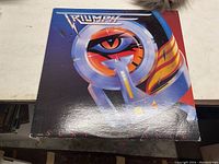 Front cover of Triumph album Surveillance showing the record sleeve with vibrant artwork and the band logo