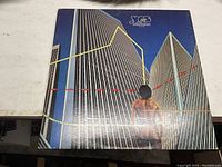 Front cover of the 'Going For The One' album by Yes showing the partial nude figure and cityscape with lines