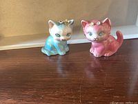 Front view of blue and pink kitten salt and pepper shakers with floral decorations on their heads.
