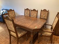 Six decorative wooden dining chairs arranged around a dining table, showing the set and style.