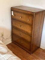 Wooden four drawer dresser angled view showing drawer knobs and wear marks.