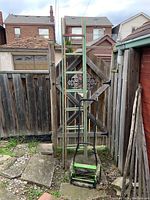 Wooden extension ladder positioned vertically against a wooden fence with visible concrete ground.