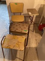 Phone chair with attached table and three stools arranged on basement floor showing overall condition and lot contents.