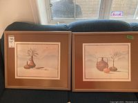 Two framed matted prints showing still life pottery and landscape, both with brown mats.