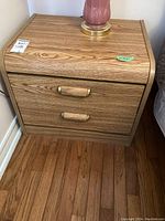 Front view of wood side table showing two drawers with brass handles and natural oak wood finish