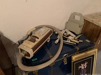 Overall view of vintage Electrolux vacuum cleaner with hose and accessories on a bench in basement.