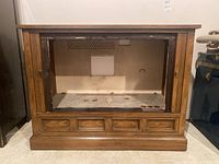 Front view of empty Zenith wood veneer TV cabinet showing open space for television and four panel drawer-like accents below.