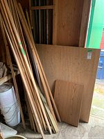 Various wood strips, 2x4s, and wood panels leaning against a wall inside a shed.