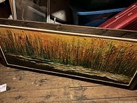 Photo of large rectangular textured wall art showing abstract nature-inspired vertical patterns in warm colors in a white frame on wooden floor.