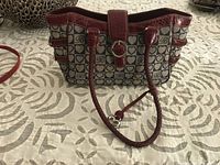 Front view of the Brighton tote bag showing heart patterned fabric with red leather trim, two handles, and silver-tone ring closure.