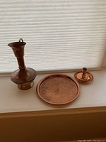 Overview photo showing all three items: copper/brass pitcher, hammered copper tray, and copper candle holder with tray