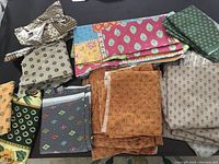 Multiple folded and stacked pieces of cotton fabric with various colors and patterns visible, representing a lot of fabric pieces.