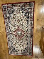 Top view of the Ikea wool carpet showing the floral medallion pattern and color scheme on a wooden floor.