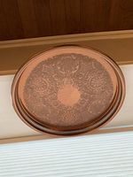 Top-down view of large round copper tray showing the ornate etched pattern and decorative rim.