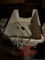 Large plastic dog crate top with metal gate and parts inside, bottom nested inside top