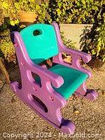 Front view of the purple and green child's rocking chair made of plastic, showing seat, backrest and rocker base.
